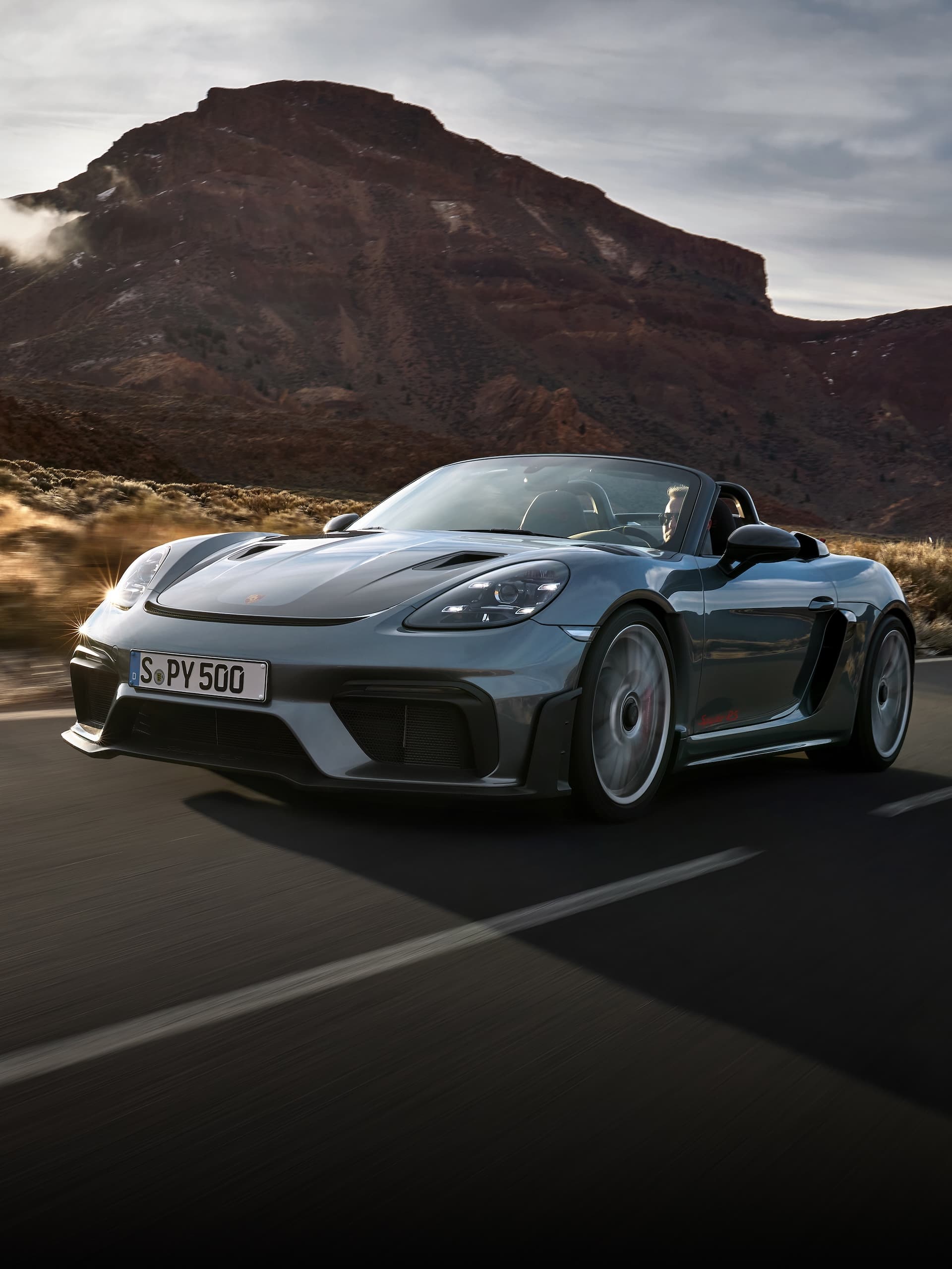 Porsche 718 Spyder RS conduciendo en carretera entre formaciones rocosas.